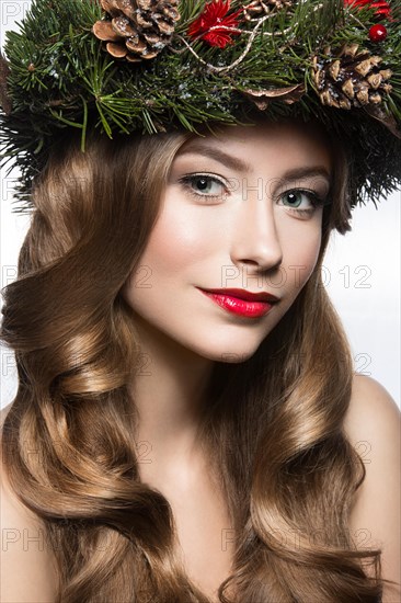 Beautiful girl with a wreath of Christmas tree branches and cones. New Year image. Beauty face. Picture taken in the studio on a white background