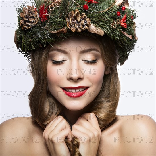 Beautiful girl with a wreath of Christmas tree branches and cones. New Year image. Beauty face. Picture taken in the studio on a white background