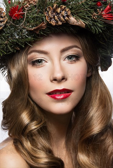 Beautiful girl with a wreath of Christmas tree branches and cones. New Year image. Beauty face. Picture taken in the studio on a white background