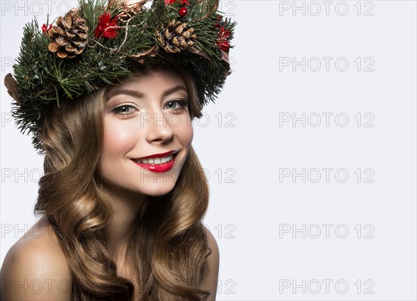 Beautiful girl with a wreath of Christmas tree branches and cones. New Year image. Beauty face. Picture taken in the studio on a white background