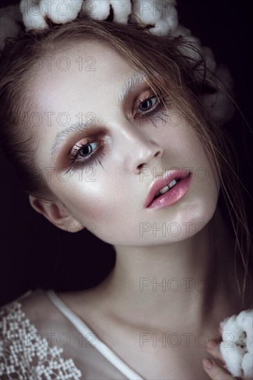 Art fashion girl with creative makeup and cotton in her hair. Beauty face. Picture taken in the studio