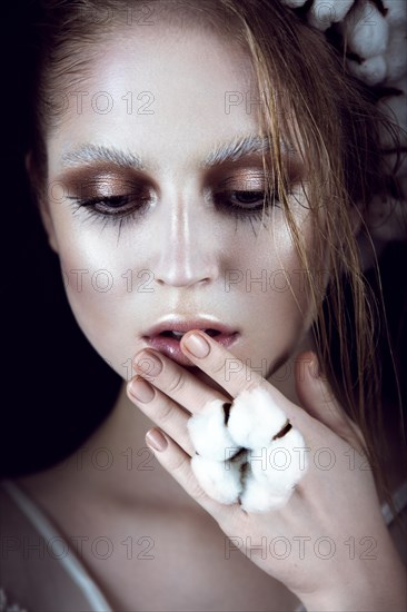 Art fashion girl with creative makeup and cotton in her hair. Beauty face. Picture taken in the studio