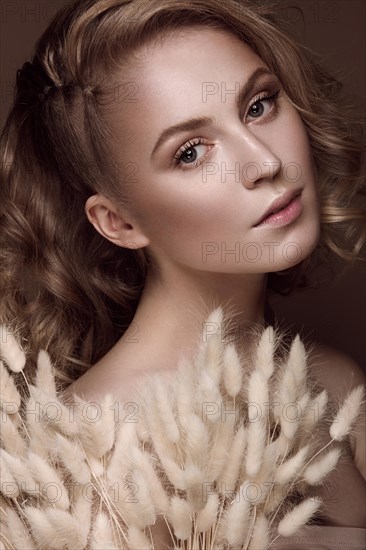 Beautiful girl with a gentle make-up and hairstyle with ears of corn in her hands. Beauty face. Picture taken in the studio