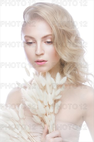 Beautiful girl with a gentle make-up and hairstyle with ears of corn in her hands. Beauty face. Picture taken in the studio