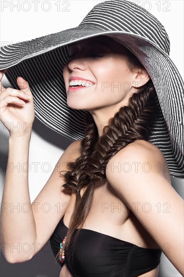 Beautiful cheerful girl in a summer beach striped hat. The beauty of the face. Photos shot in the studio