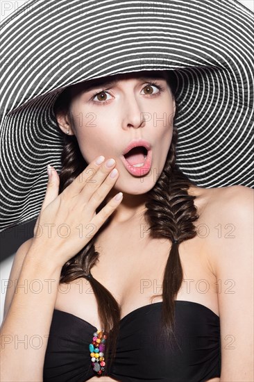 Beautiful cheerful girl in a summer beach striped hat. The beauty of the face. Photos shot in the studio