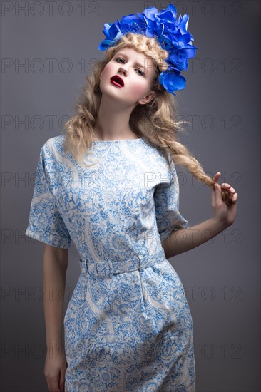 Girl with flowers on her head in a dress in the Russian style. Picture taken in the studio