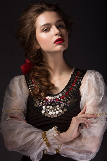 Beautiful Russian girl in national dress with a braid hairstyle and red lips. Beauty face. Picture taken in the studio on a black background