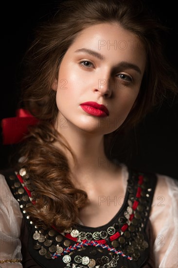 Beautiful Russian girl in national dress with a braid hairstyle and red lips. Beauty face. Picture taken in the studio on a black background