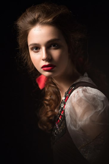 Beautiful Russian girl in national dress with a braid hairstyle and red lips. Beauty face. Picture taken in the studio on a black background