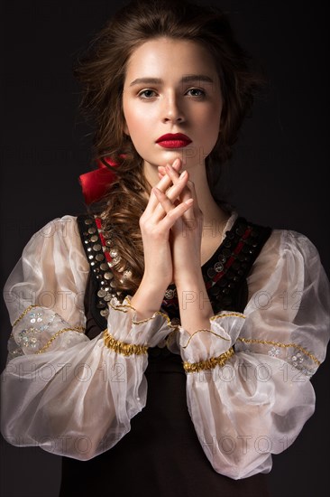 Beautiful Russian girl in national dress with a braid hairstyle and red lips. Beauty face. Picture taken in the studio on a black background