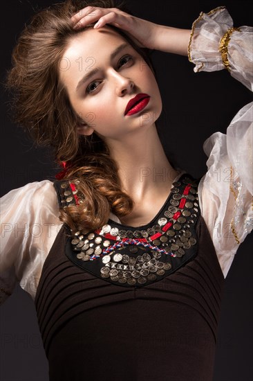 Beautiful Russian girl in national dress with a braid hairstyle and red lips. Beauty face. Picture taken in the studio on a black background