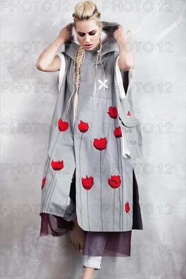 Creative unusual blond girl in designer clothes and braids on her head posing in the studio