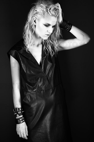 Daring girl model in black leather dress in the style of rock