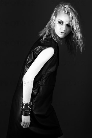 Daring girl model in black leather dress in the style of rock