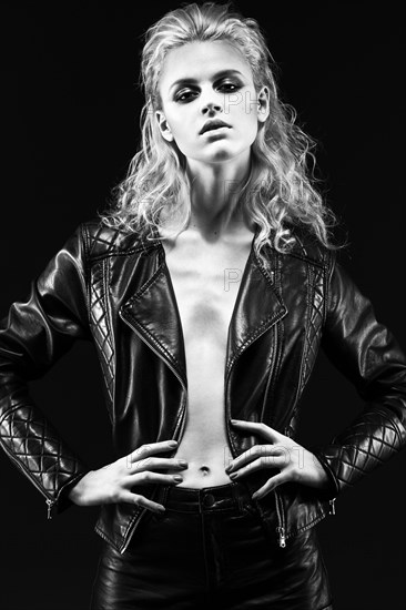 Daring girl model in black leather dress in the style of a rock on a naked body