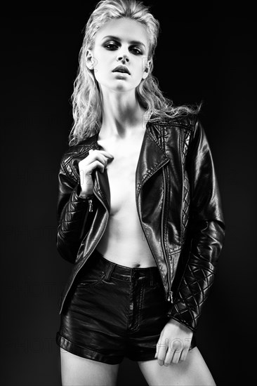 Daring girl model in black leather dress in the style of a rock on a naked body