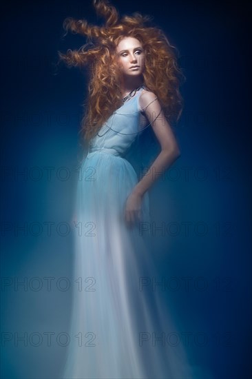 Beautiful fashionable red-haired girl in transparent dress with creative hairstyle curls