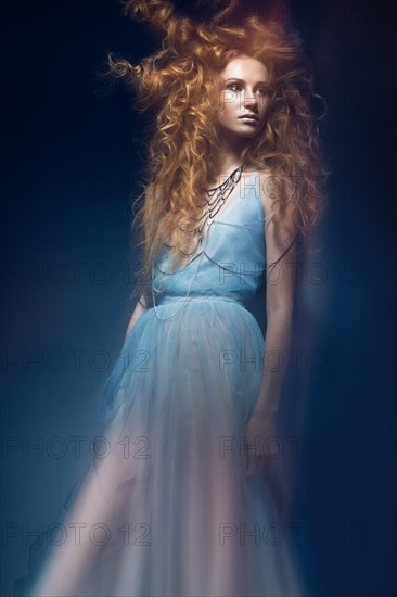 Beautiful fashionable red-haired girl in transparent dress with creative hairstyle curls