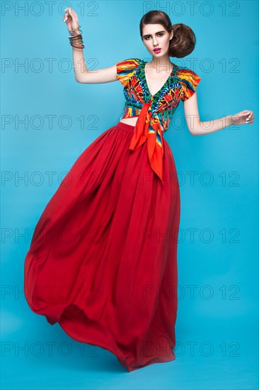 Beautiful fashionable woman an unusual hairstyle in bright clothes and colorful accessories. Cuban style. Picture taken in the studio on a bright background