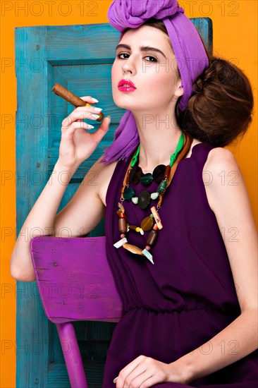 Beautiful fashionable woman an unusual hairstyle in bright clothes and colorful accessories. Cuban style. Picture taken in the studio on a bright background
