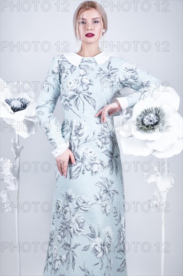 Beautiful girl with vintage make-up and hairstyle in a warm winter woolen dress. decoration of flowers. The beauty of the face. Photos shot in studio