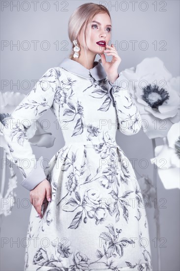 Beautiful girl with vintage make-up and hairstyle in a warm winter woolen dress. decoration of flowers. The beauty of the face. Photos shot in studio