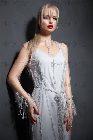 Beautiful girl in designer fashionable transparent clothes posing in studio. Beauty of face and body