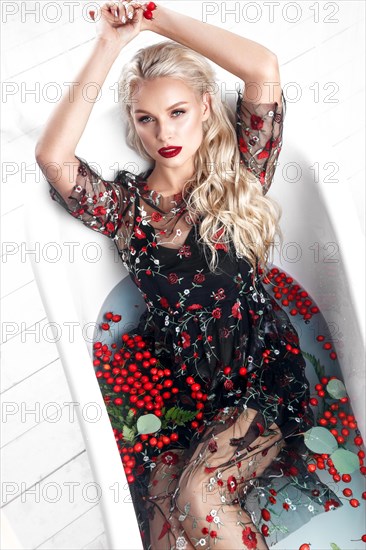 Beautiful girl in a summer dress in the bathroom with flowers. Beauty face. Photo taken in the studio