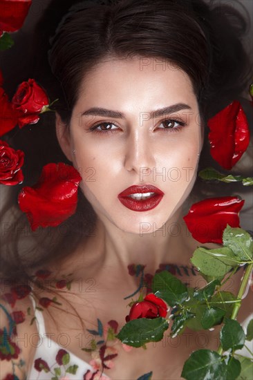 Beautiful girl with classic make-up and red lips in the bathroom with flowers. Beauty face. Photo taken in the studio