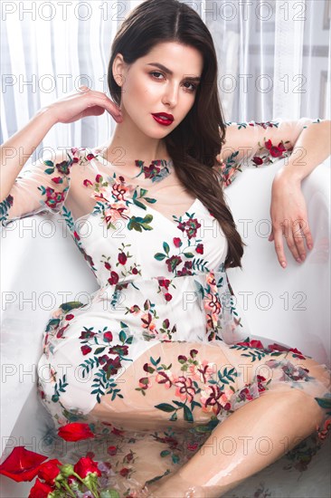 Beautiful girl in a summer dress in the bathroom with flowers. Beauty face. Photo taken in the studio