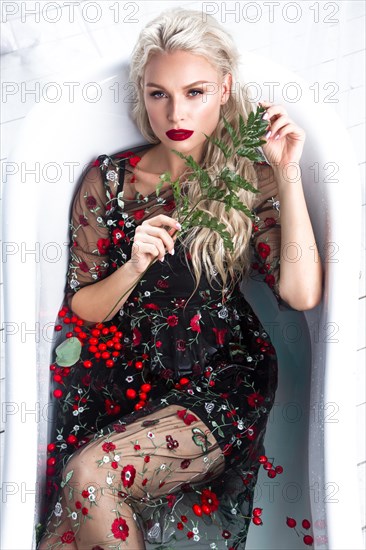 Beautiful girl in a summer dress in the bathroom with flowers. Beauty face. Photo taken in the studio