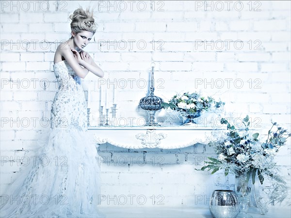 Beautiful girl in white dress in the image of the Snow Queen with a crown on her head. Picture taken in the studio with decorations