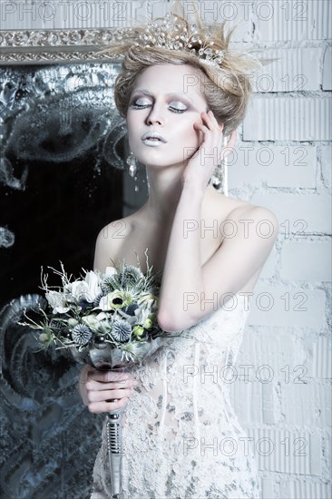 Beautiful girl in white dress in the image of the Snow Queen with a crown on her head. Picture taken in the studio with decorations