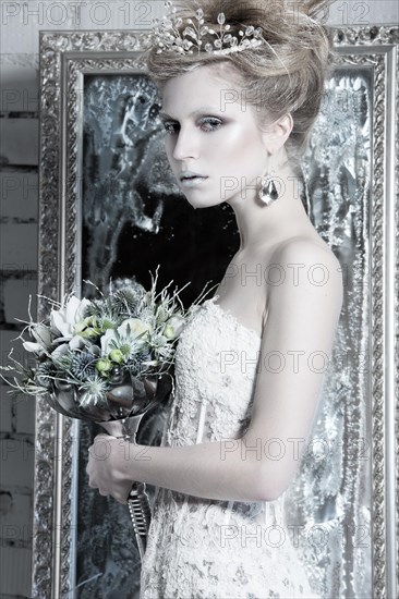 Beautiful girl in white dress in the image of the Snow Queen with a crown on her head. Picture taken in the studio with decorations