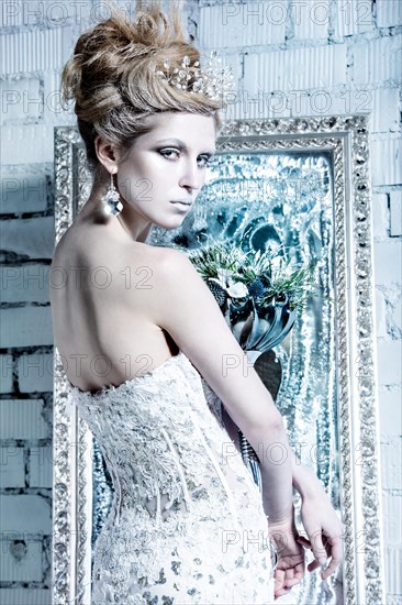 Beautiful girl in white dress in the image of the Snow Queen with a crown on her head. Picture taken in the studio with decorations