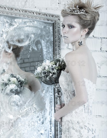 Beautiful girl in white dress in the image of the Snow Queen with a crown on her head. Picture taken in the studio with decorations