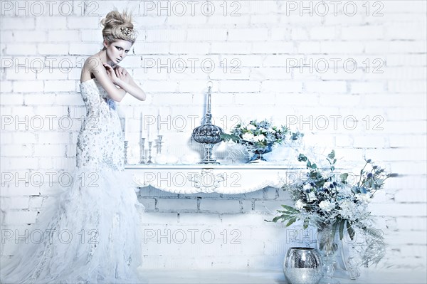 Beautiful girl in white dress in the image of the Snow Queen with a crown on her head. Picture taken in the studio with decorations