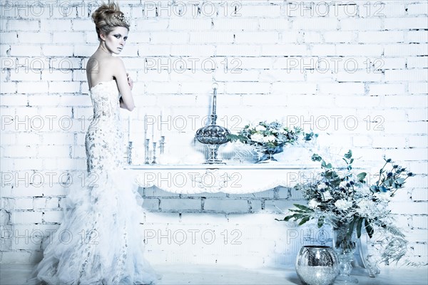 Beautiful girl in white dress in the image of the Snow Queen with a crown on her head. Picture taken in the studio with decorations