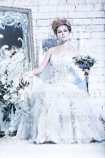 Beautiful girl in white dress in the image of the Snow Queen with a crown on her head. Picture taken in the studio with decorations