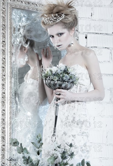 Beautiful girl in white dress in the image of the Snow Queen with a crown on her head. Picture taken in the studio with decorations