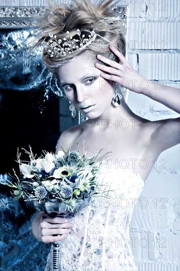 Beautiful girl in white dress in the image of the Snow Queen with a crown on her head. Picture taken in the studio with decorations