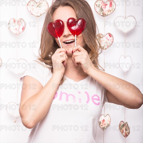 Valentines Day. Funny beautiful Woman holding candy in the form of heart. Beauty face. Picture taken in the studio with decorations