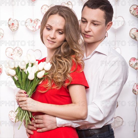 Beautiful young couple in love with a bouquet of flowers. Valentine's Day. Picture taken in the studio