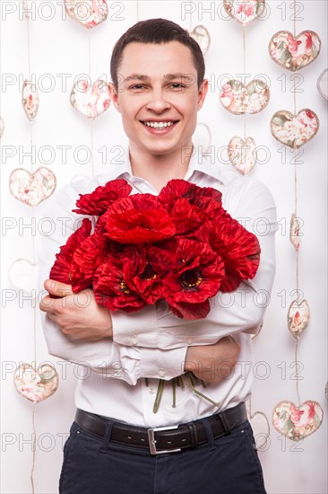 Beautiful young man in love with a bouquet of flowers. Valentine's Day. Picture taken in the studio