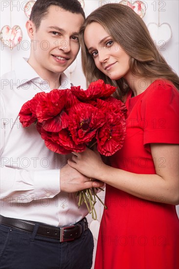 Beautiful young couple in love with a bouquet of flowers. Valentine's Day. Picture taken in the studio