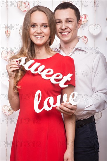 Beautiful young couple in love with the words Sweet love showing the form of heart hands. Valentine's Day. Picture taken in the studio
