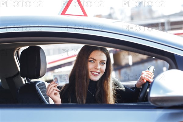 Joyful girl driving a training car with a drivers license card in her hands