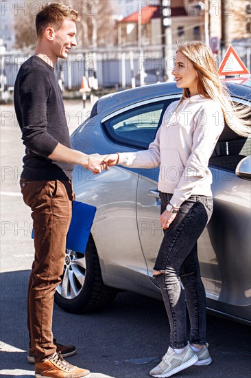 Acquaintance of a driving instructor and a student near a training car. Lesson at the circuit