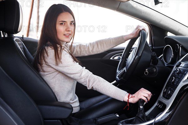 Young beautiful happy woman sitting at the wheel new car